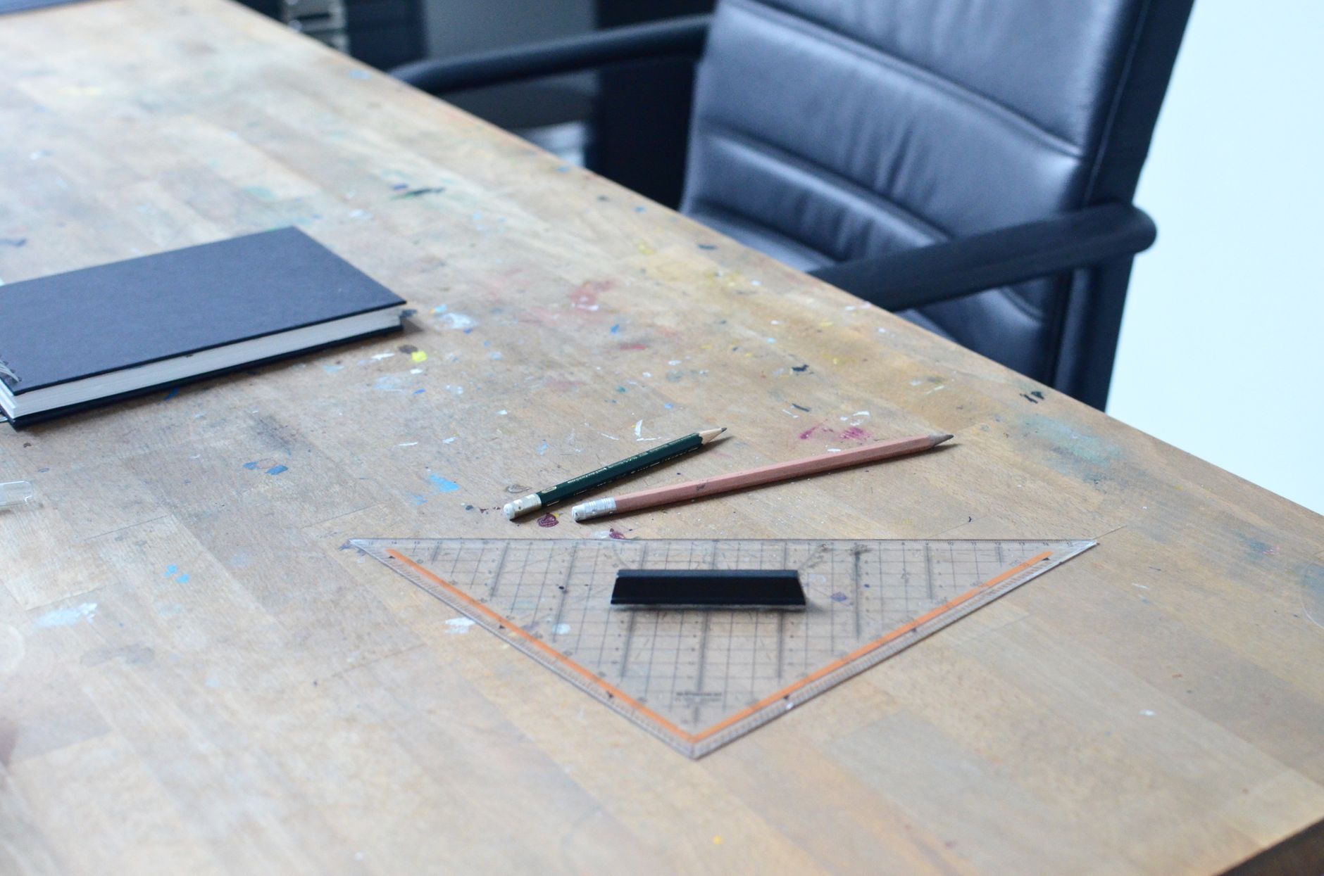 Studio worktable with sketchbook, pencils, and a drafting triangle